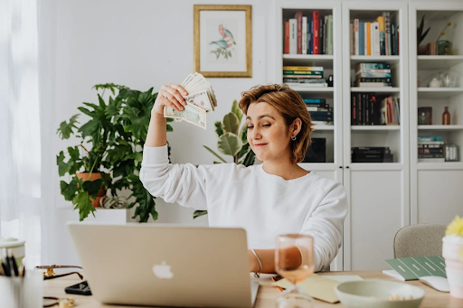 woman waving cash at laptop