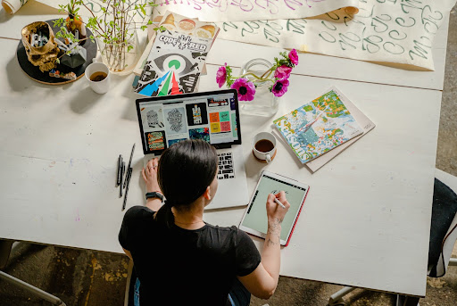 woman writing on tablet working on laptop