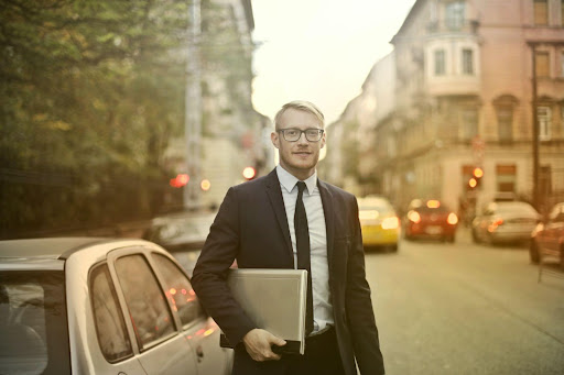 Man standing in street holding laptop under his arm