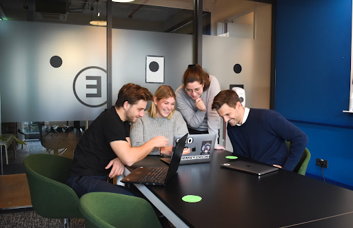 people sat round a desk looking at laptop