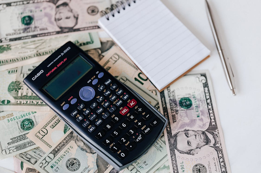 notepad and calculator on top of dollar notes