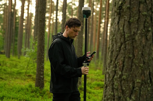 man using survey equipment in forest