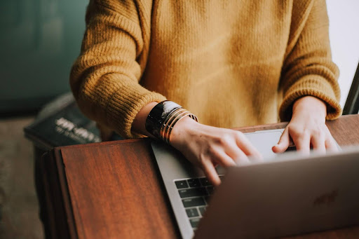 person in mustard top using laptop
