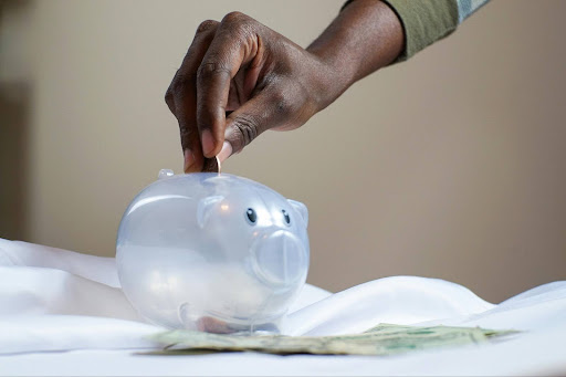 hand putting coin in piggy bank